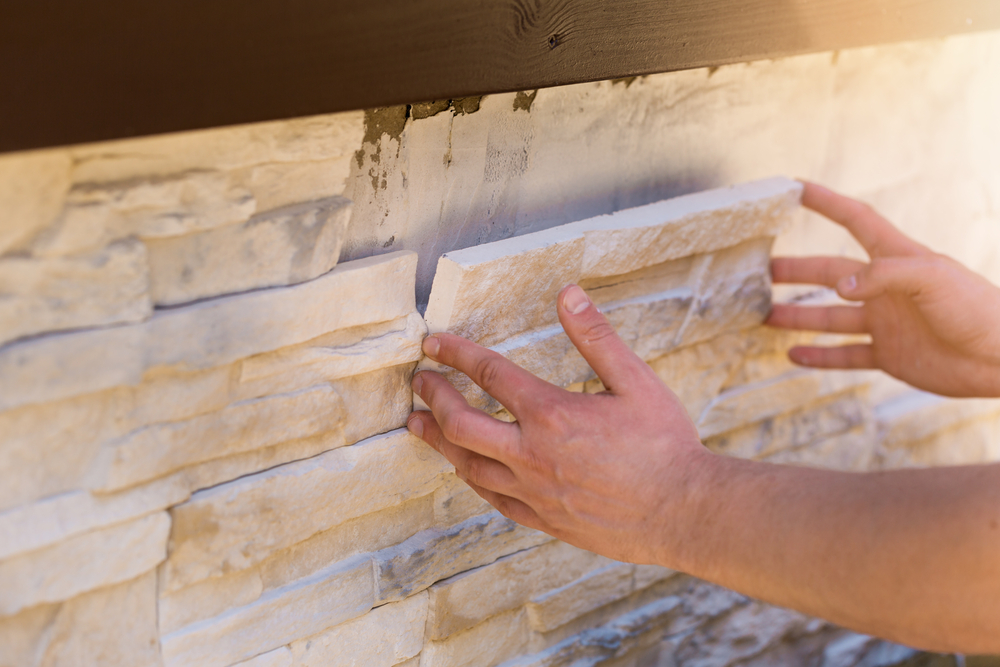 A professional contractor performing stone veneer installation on the exterior of a home
